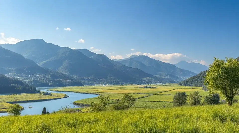 青空の下、山並みと草地の間を川が流れる風景（イメージ写真）